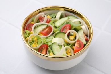 Bowl of tasty salad with leek, tomatoes and cucumbers on white tiled table, closeup