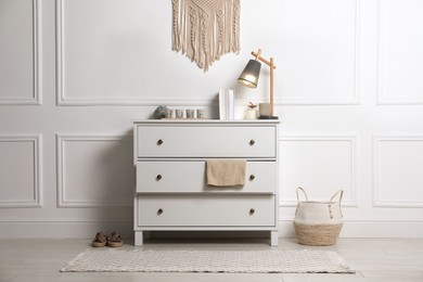 Stylish room interior with chest of drawers near white wall