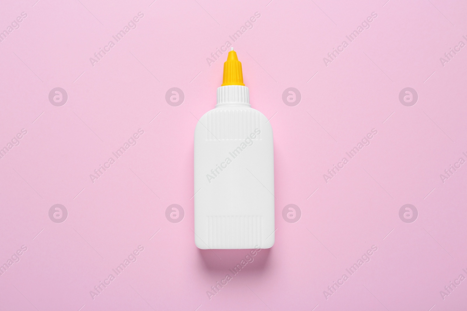 Photo of Bottle of glue on pink background, top view