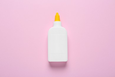 Bottle of glue on pink background, top view