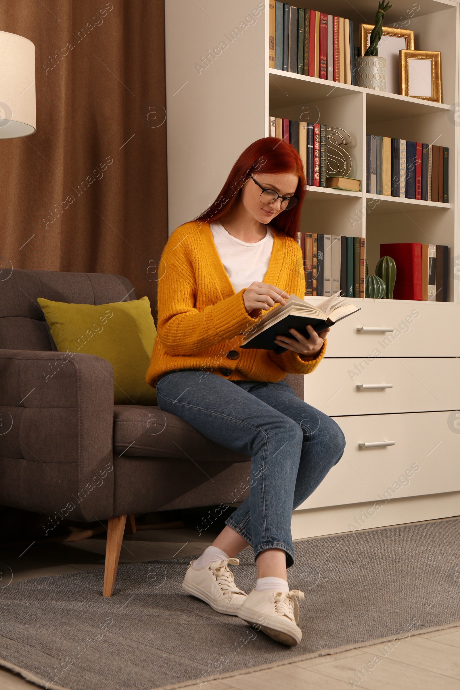 Photo of Beautiful young woman reading book in armchair indoors. Home library