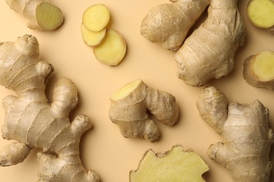 Photo of Fresh ginger with green leaves on beige background, flat lay