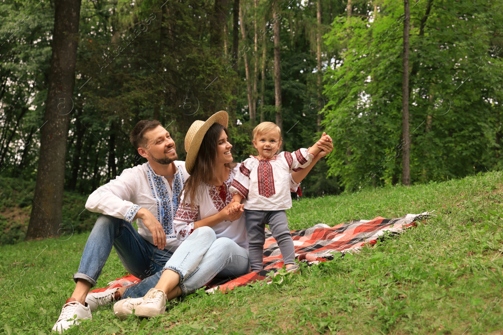 Photo of Happy family in Ukrainian national clothes on green grass outdoors