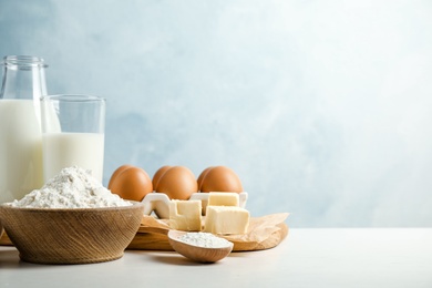 Fresh ingredients for delicious homemade cake on white wooden table against blue background. Space for text