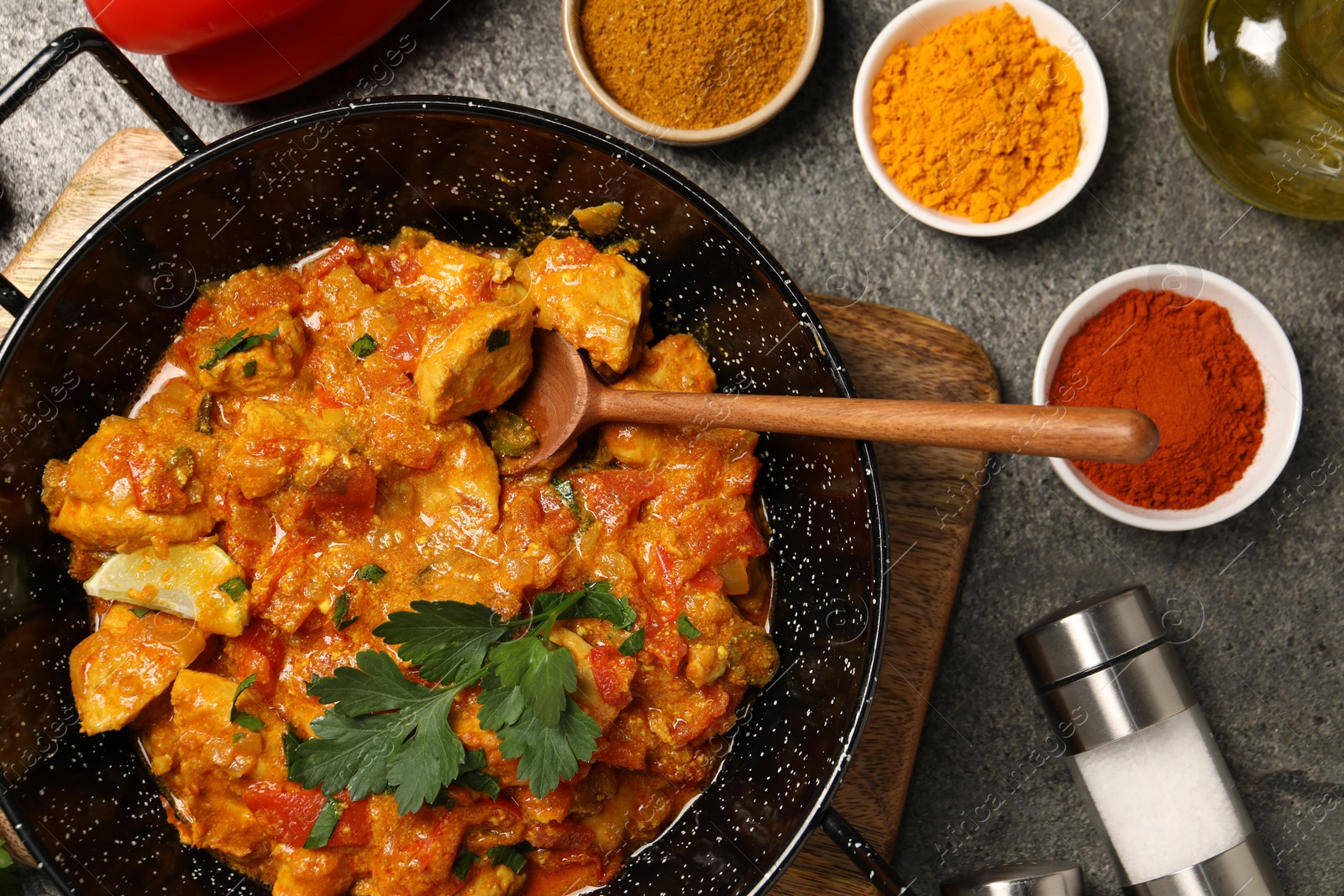 Photo of Delicious chicken curry and spices on grey table, flat lay