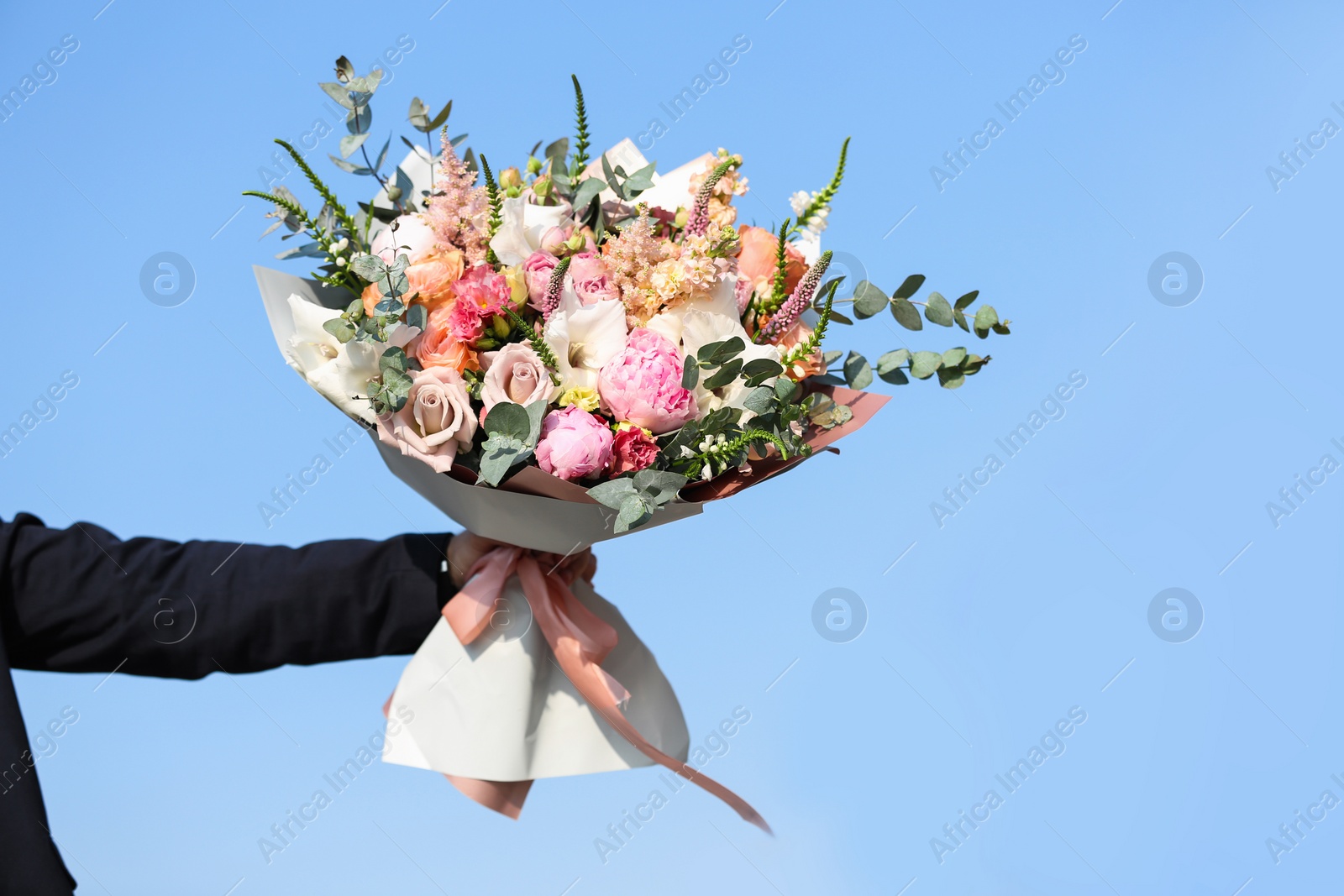 Photo of Man holding beautiful flower bouquet on street, closeup view