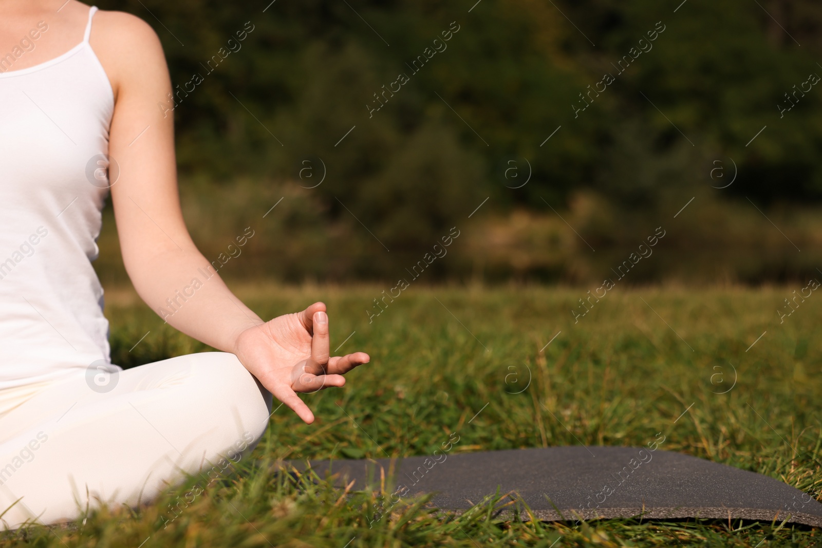 Photo of Woman practicing yoga on mat outdoors, closeup and space for text. Lotus pose