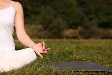 Woman practicing yoga on mat outdoors, closeup and space for text. Lotus pose