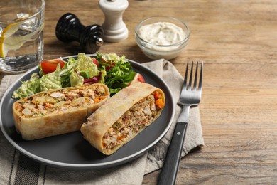 Photo of Pieces of tasty strudel with chicken, vegetables and salad on wooden table. Space for text