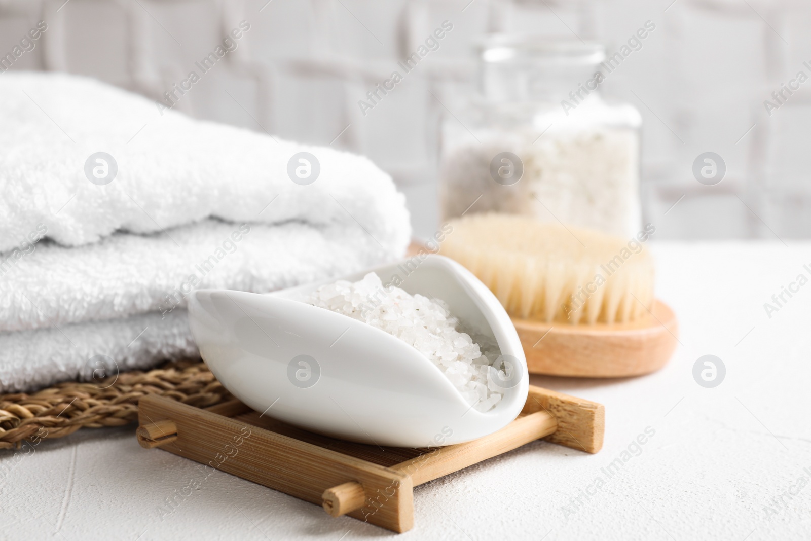 Photo of Sea salt for spa scrubbing procedure in bowl on white table
