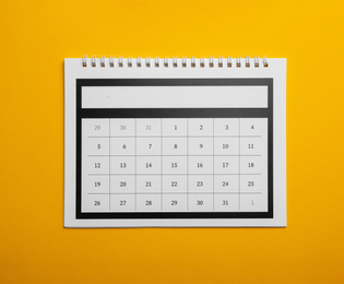 Photo of Paper calendar on yellow background, top view
