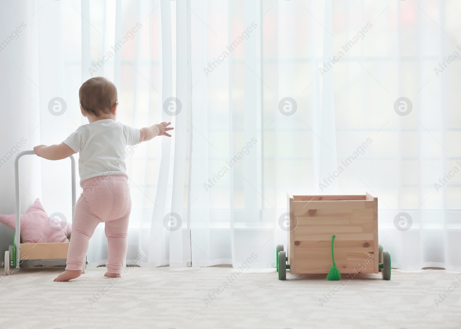 Photo of Cute baby with toy walker at home