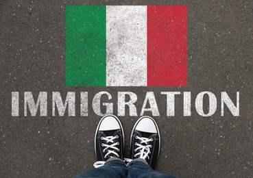 Image of Immigration. Woman standing on asphalt near flag of Italy, top view