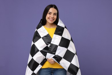 Happy young woman with checkered flag on violet background