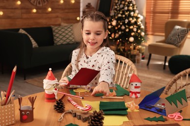 Cute child making Christmas greeting card at home