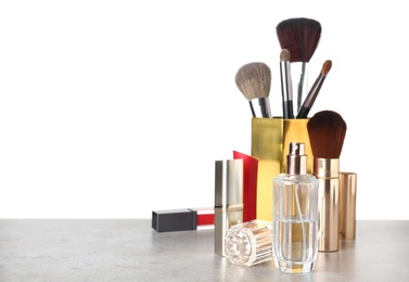 Composition with bottle of perfume and makeup products on table against white background