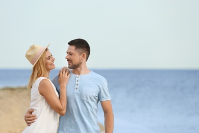 Happy romantic couple spending time together on beach, space for text