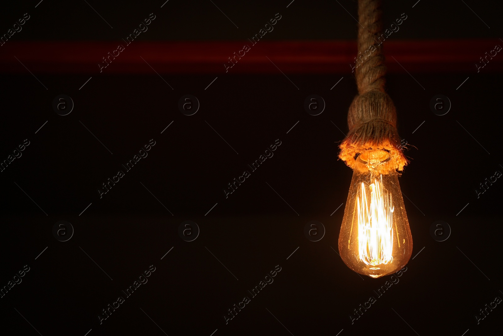 Photo of Creative pendant lamp in dark room, closeup. Space for text