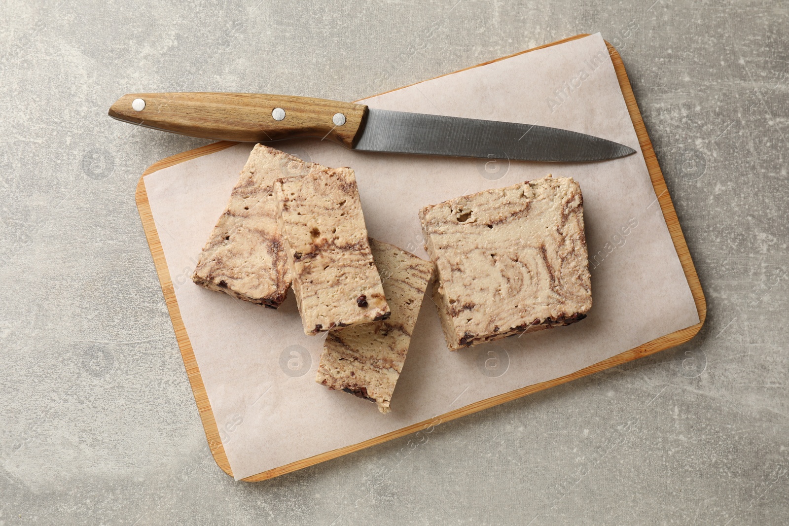 Photo of Tasty chocolate halva and knife on grey table, top view