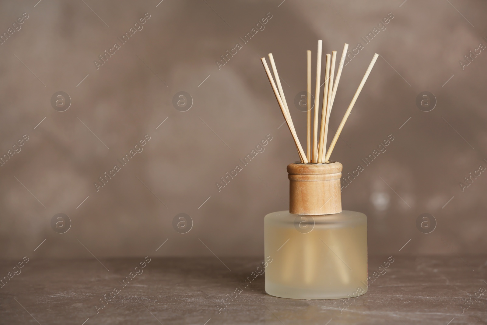 Photo of Aromatic reed freshener on table against grey background