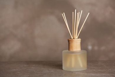 Photo of Aromatic reed freshener on table against grey background