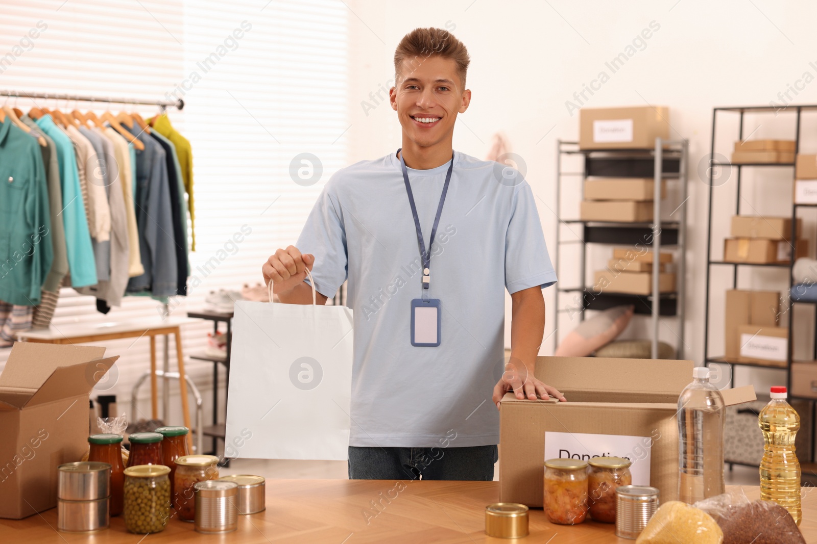 Photo of Volunteer with paper bag and food products at table in warehouse