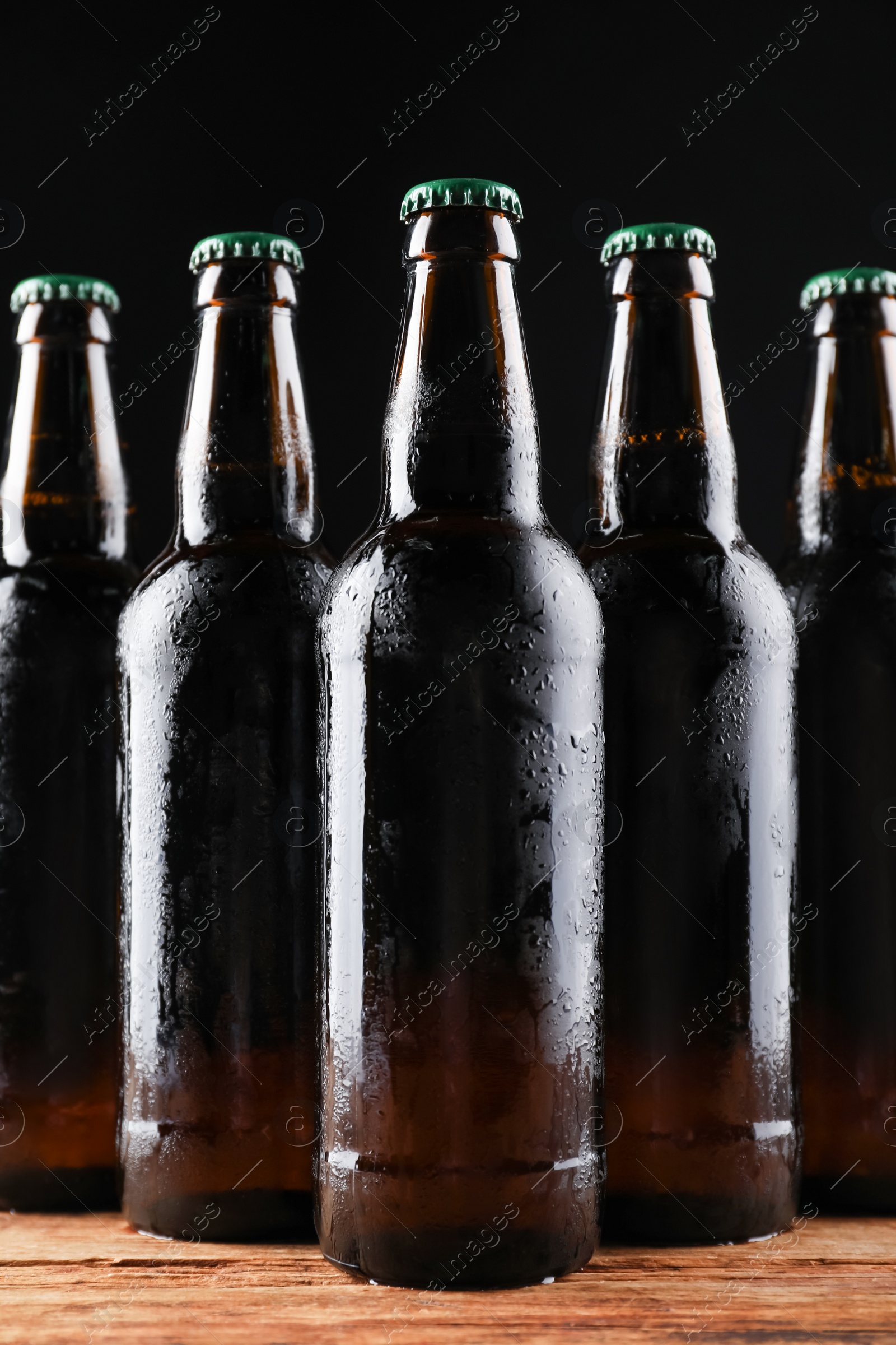 Photo of Many bottles of beer on wooden table against dark background