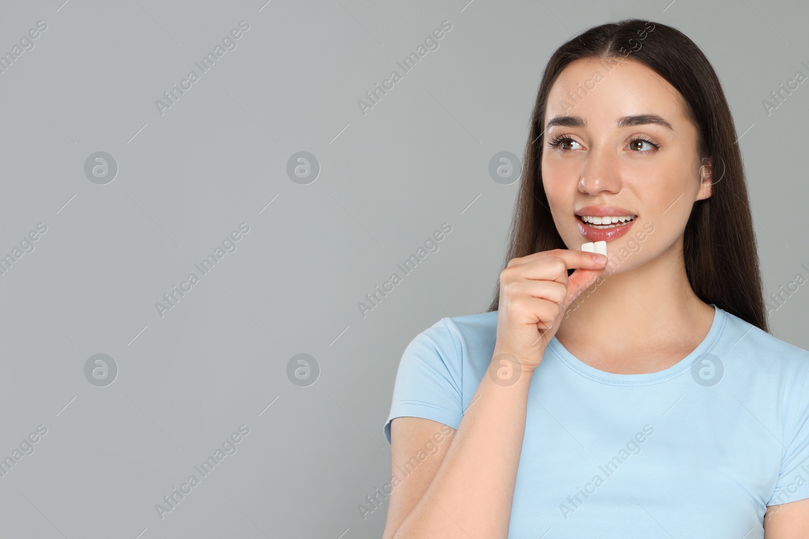 Photo of Young woman with bubble gums on grey background. Space for text