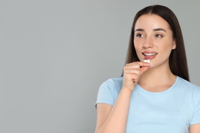 Photo of Young woman with bubble gums on grey background. Space for text