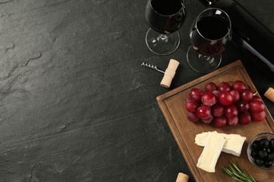 Flat lay composition with red wine and snacks on black table, space for text