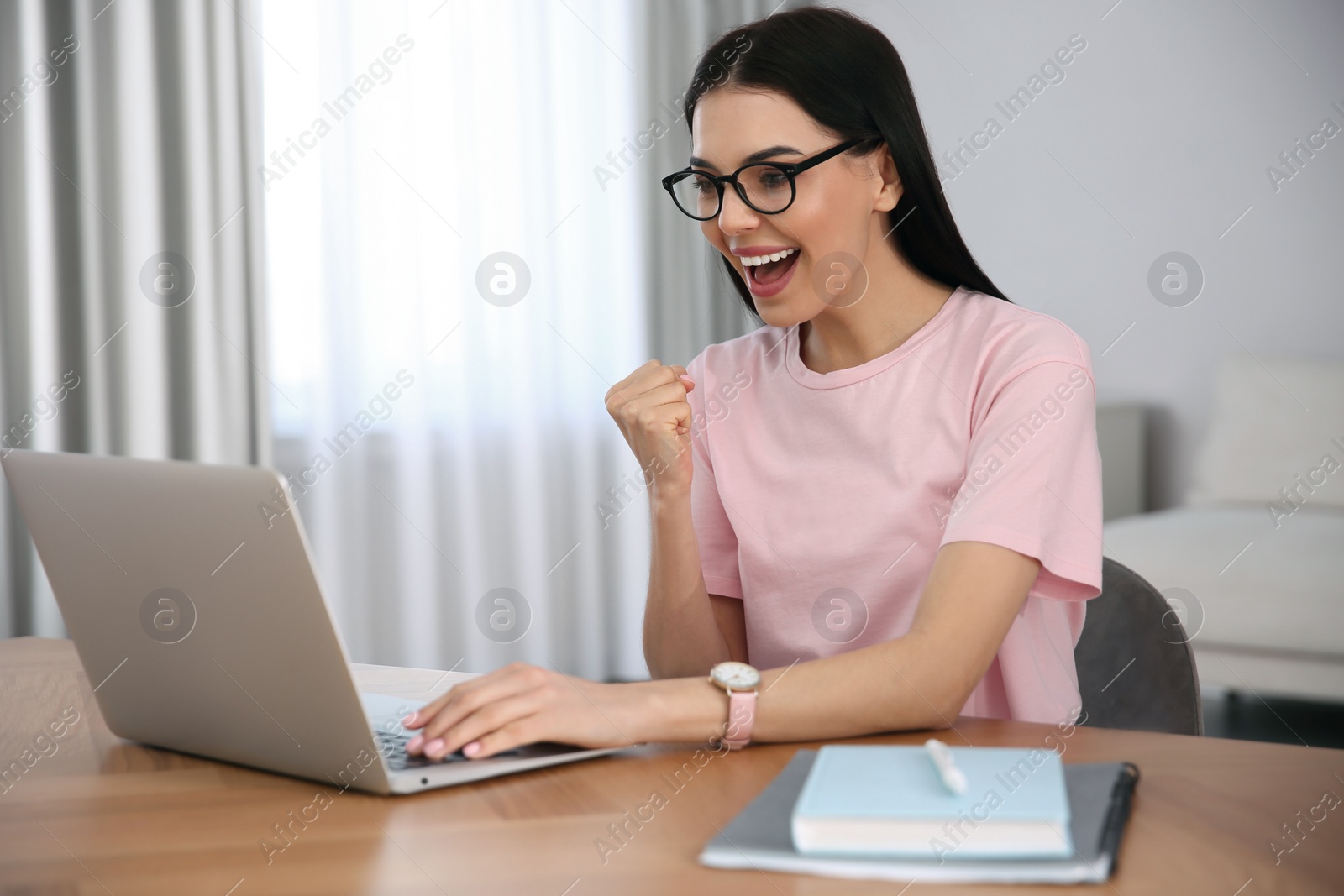 Photo of Emotional woman participating in online auction using laptop at home