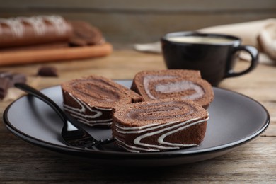 Tasty chocolate cake roll with cream on wooden table, closeup