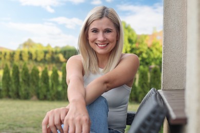 Portrait of beautiful woman sitting near house in yard, space for text