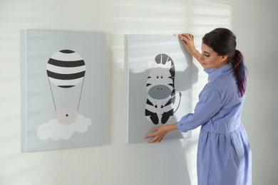 Photo of Decorator hanging picture on white wall. Children's room interior design