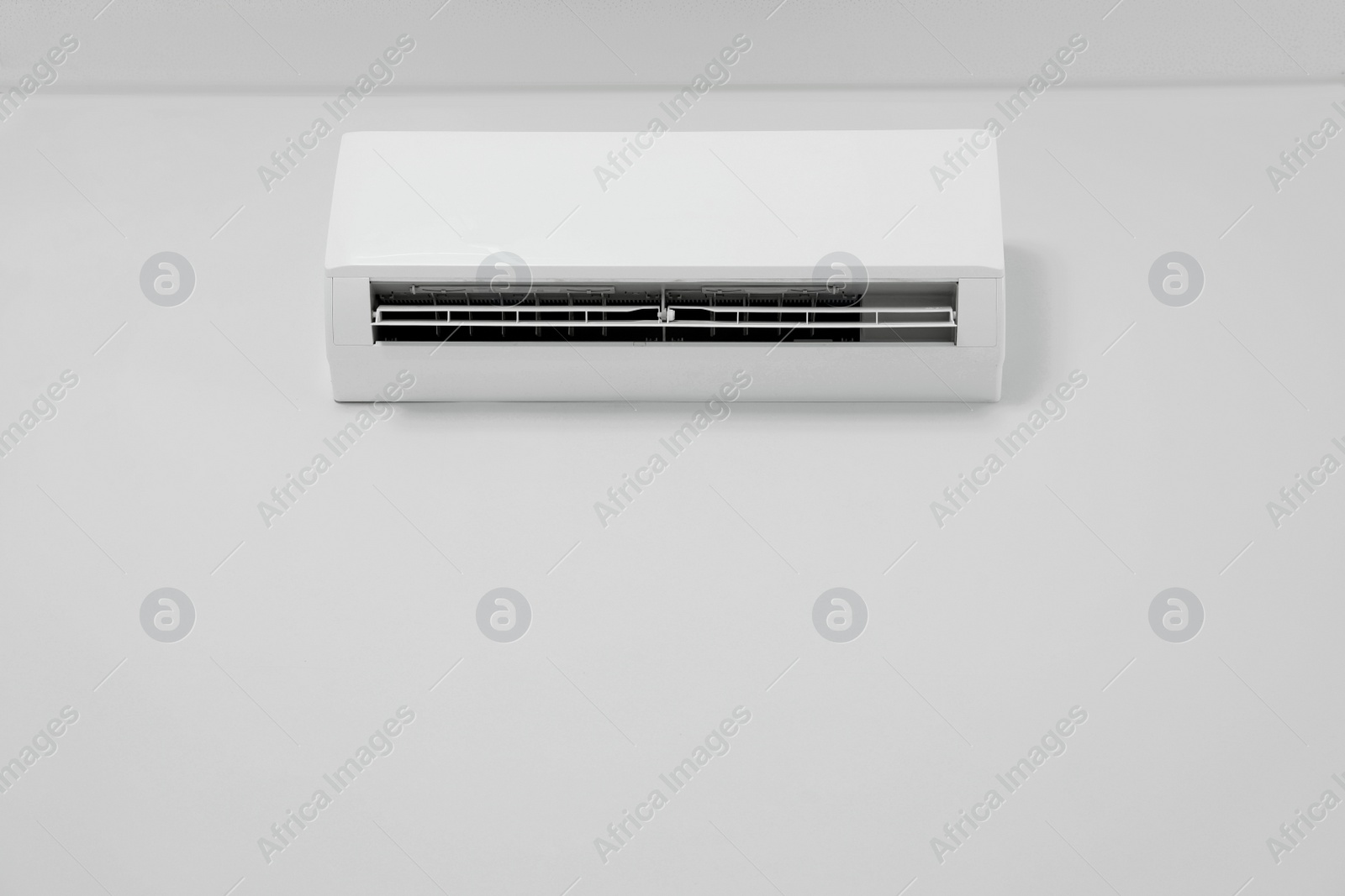 Photo of Modern air conditioner on white wall indoors, low angle view. Space for text