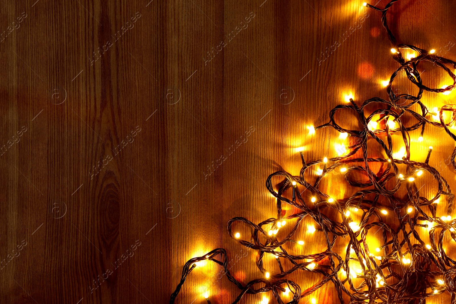 Photo of Beautiful bright Christmas lights on wooden background, flat lay. Space for text