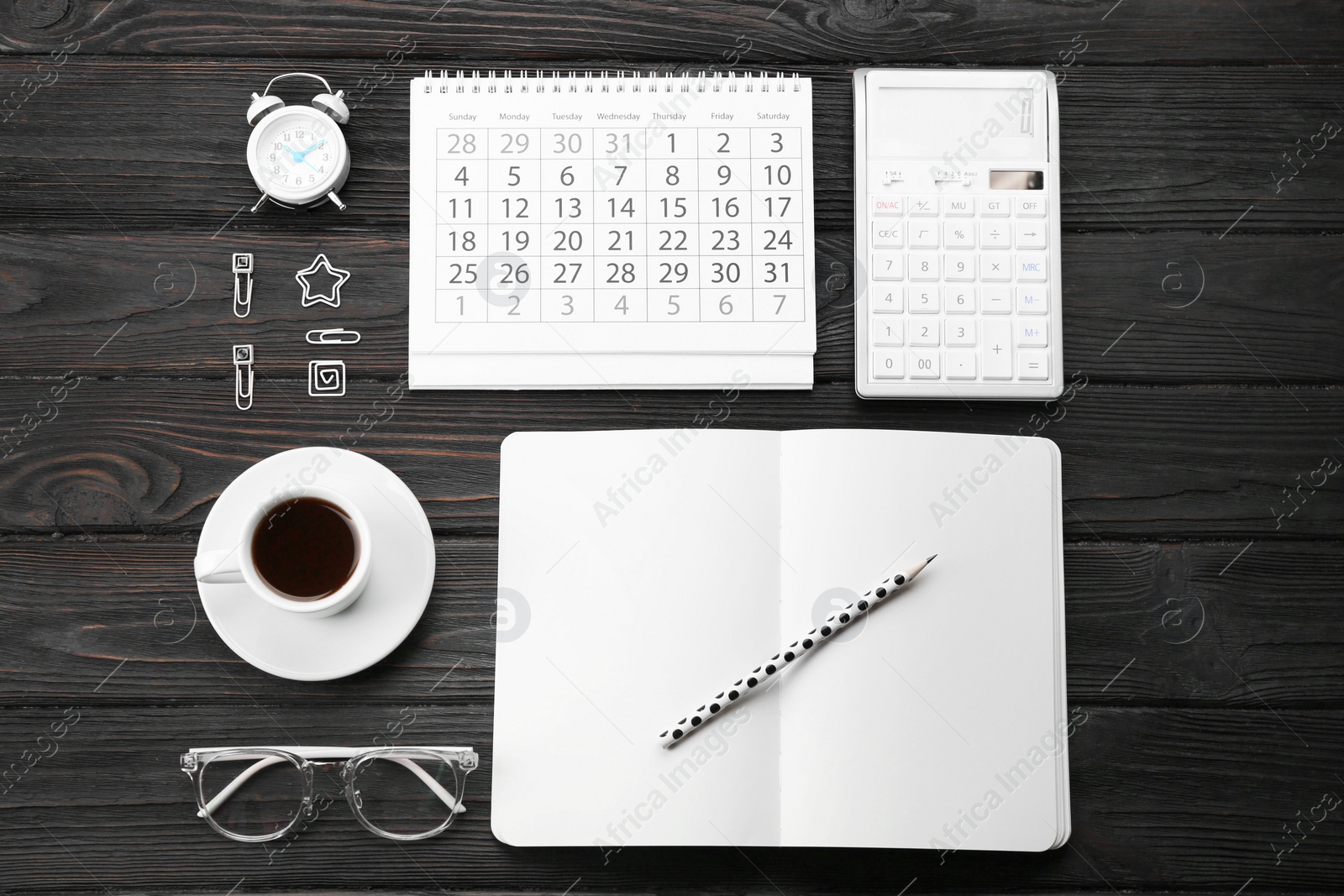 Photo of Flat lay composition with calendar and cup of coffee on black wooden table