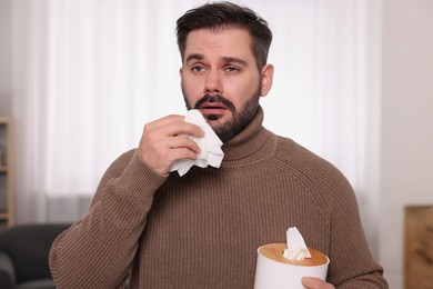 Sick man with tissues at home. Cold symptoms