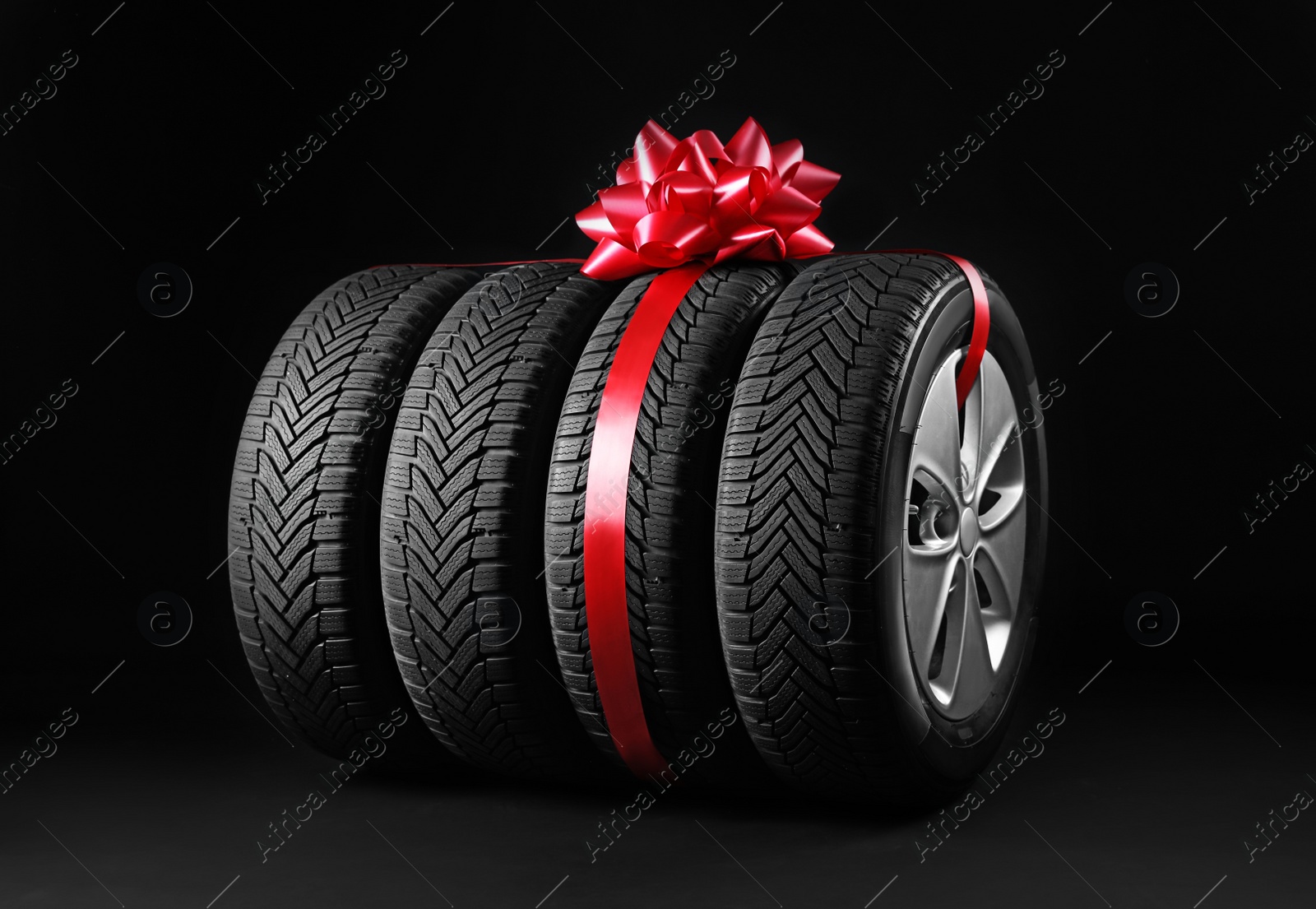 Photo of Gift set of wheels with winter tires on black background