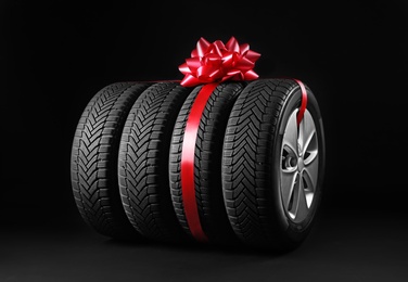 Photo of Gift set of wheels with winter tires on black background