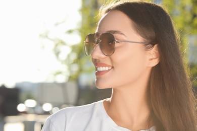 Photo of Beautiful smiling woman in sunglasses outdoors, space for text