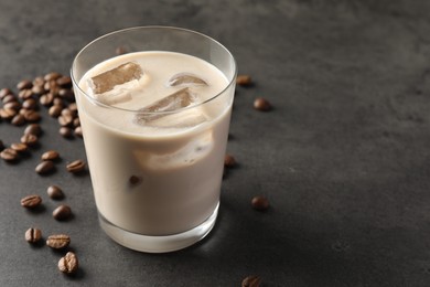 Photo of Coffee cream liqueur in glass and beans on grey table, space for text