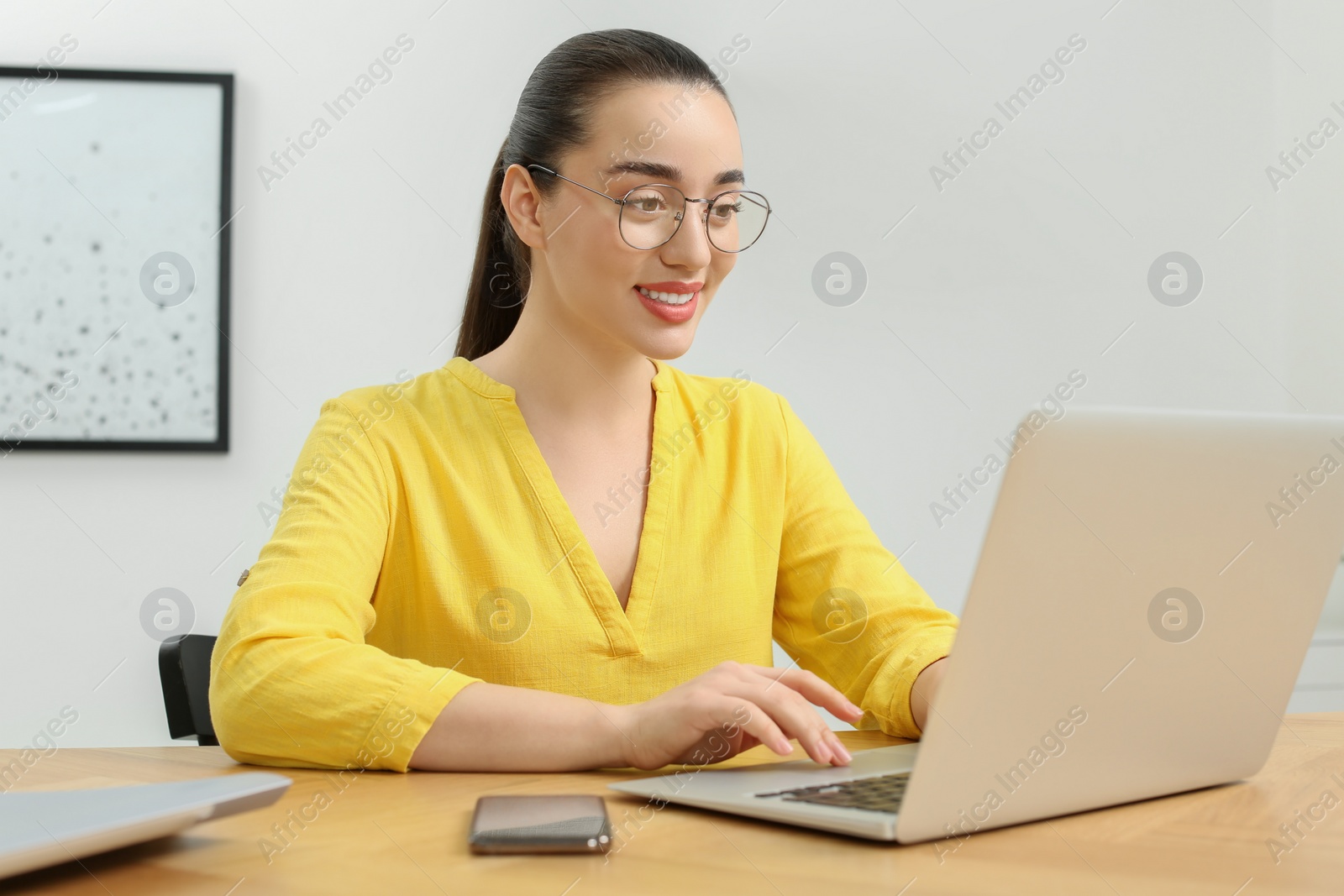 Photo of Home workplace. Happy woman working on laptop at wooden desk in room