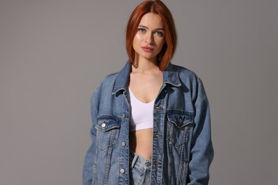 Photo of Beautiful young woman in denim jacket on gray background