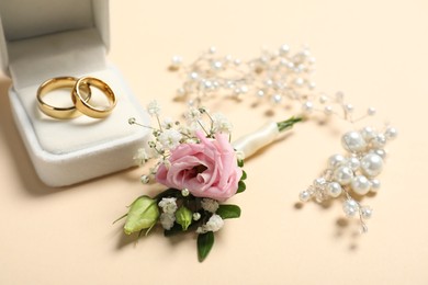 Wedding stuff. Stylish boutonniere, rings and decor on beige background, closeup