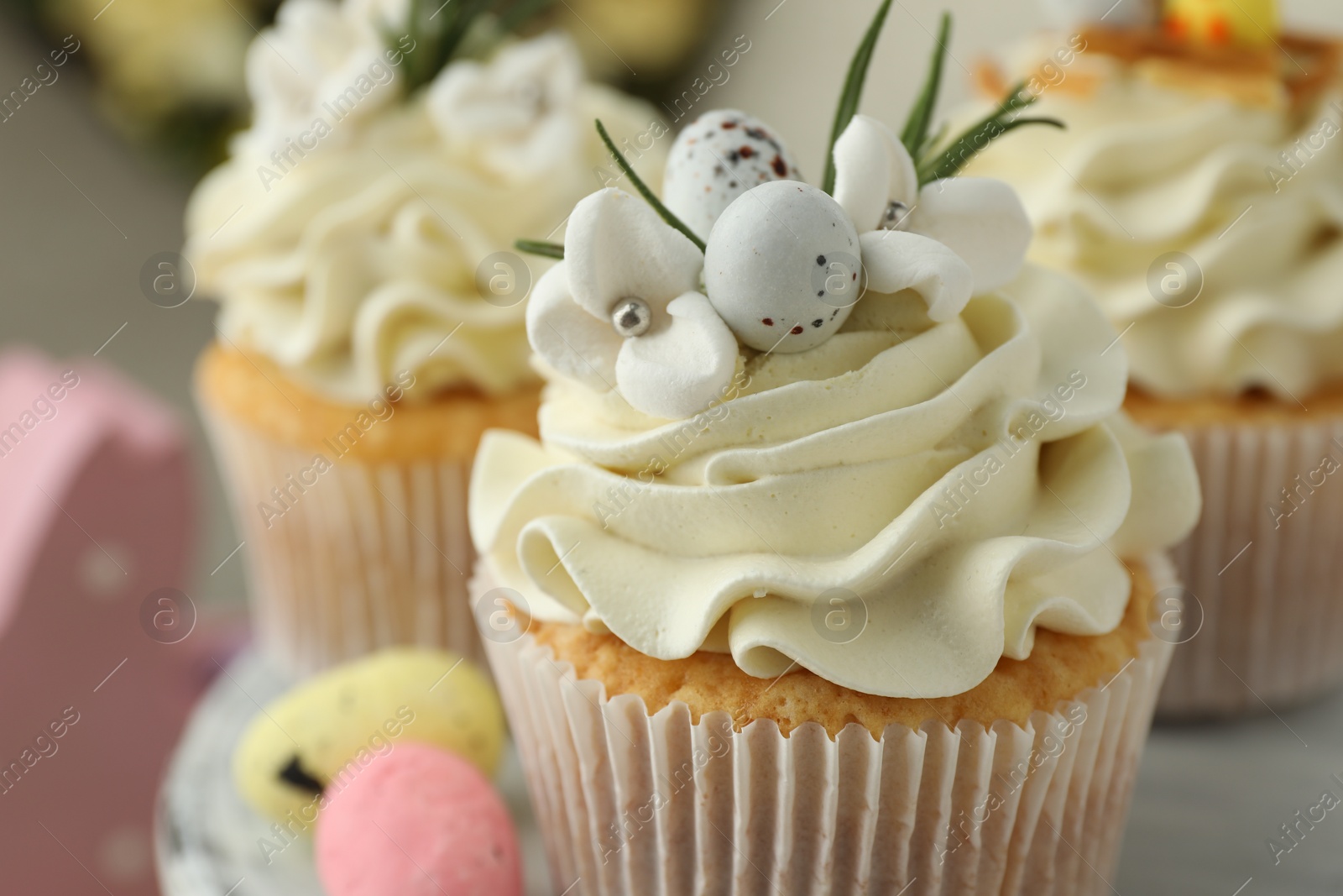 Photo of Tasty Easter cupcakes with vanilla cream on table, closeup