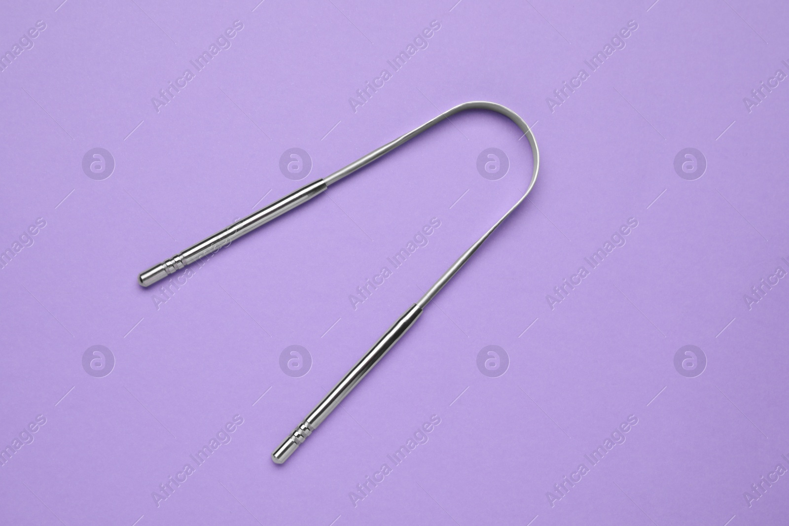 Photo of Metal tongue cleaner on violet background, top view