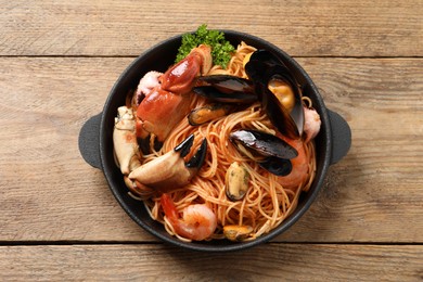 Photo of Delicious spaghetti with seafood served on wooden table, top view