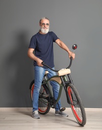 Portrait of handsome mature man with bicycle near color wall