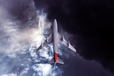 Image of Airplane flying in cloudy sky during thunderstorm